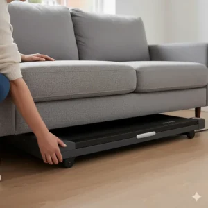 An illustration of a slim, compact under desk treadmill being slid horizontally under a sofa for space-saving storage.