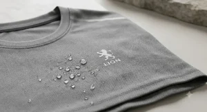 Alt text for image 2: A close-up of a grey, breathable men’s running t-shirt showing water-repellent fabric detail and 'LION' logo.