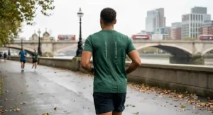 Alt text for image 3: Rear view of a man running with a lightweight, ergonomic green technical t-shirt with distinctive reflective strips.