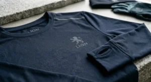 Alt text for image 8: Close-up view of a dark navy long-sleeve men’s running t-shirt with thumbholes and small reflective detail.