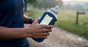 A close-up view of the elasticated blue sleeve of the running bottle, with a translucent, secure touchscreen window holding a smartphone in a protective pouch.