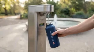Eco-conscious runner filling up a reusable insulated running bottle at a public water fountain in the UK.