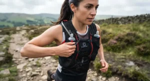 Close-up of a runner adjusting the front bungee closure system on a Salomon active skin hydration vest during a training run.