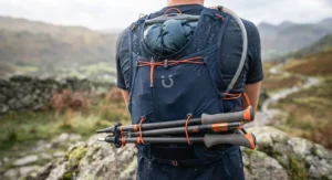 Folding trekking poles securely attached to the rear of a race vest for ultramarathon mountain running.