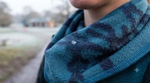 Close-up of a moisture droplet on the surface of a patterned fleece neck buff, demonstrating wicking properties while worn in a frosty park.