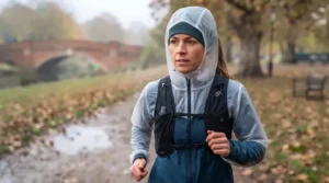 A slimline thermal running hat worn comfortably underneath a waterproof running jacket hood on a rainy UK day.