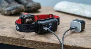 A USB rechargeable running headtorch plugged into a cable, showing a convenient power-up solution for cost-conscious runners.