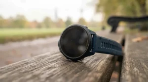A durable GPS running watch resting on a wooden bench after a long-distance training session