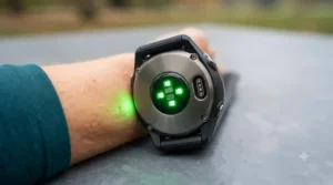 Wrist-based optical heart rate sensor flashing green light on the back of a running fitness tracker.