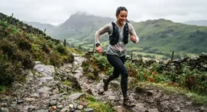 A runner navigating a muddy path in the countryside while checking pace on their Suunto running watch.