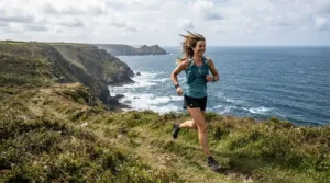 Athlete testing bone conduction vs wireless earbuds for running on a windy Cornwall coastal path